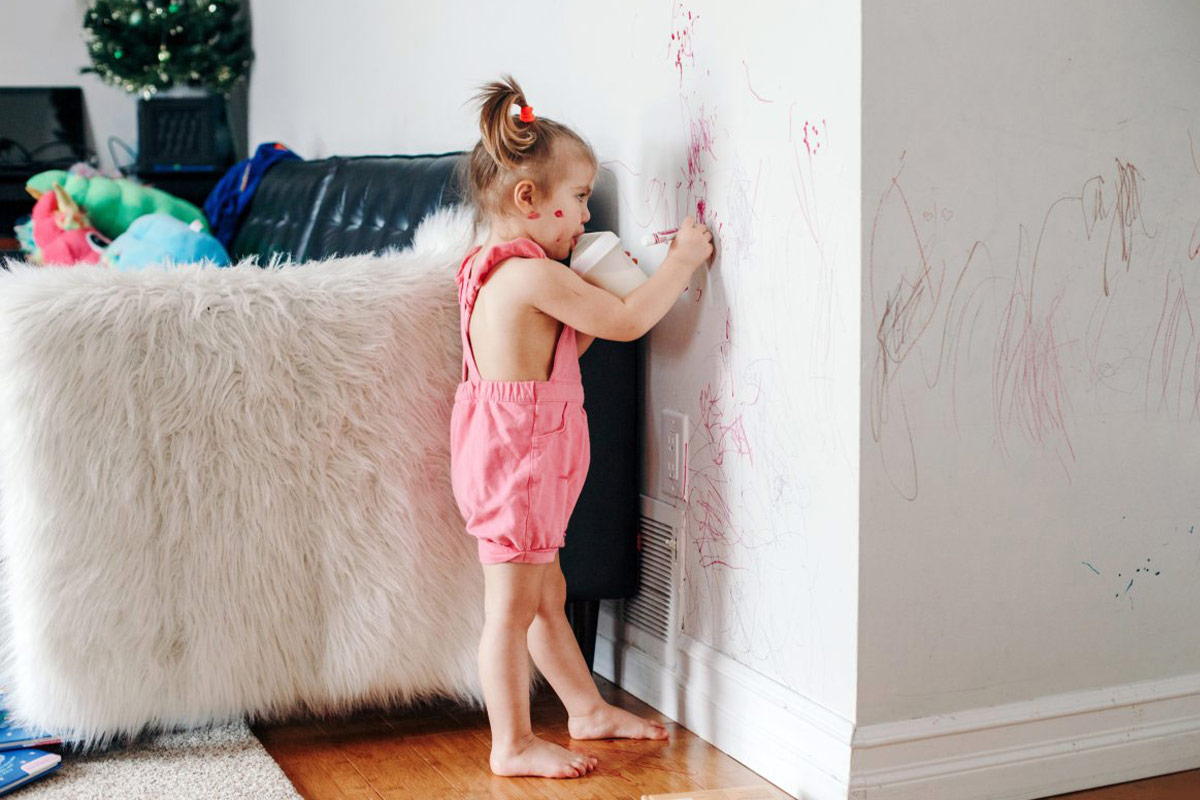 Little girl drawing on wall